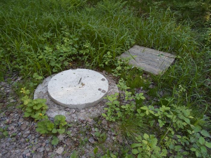 канализационный люк в траве. ливневый люк забетонированный. люк в поле. открытый люк ночью. канализационный люк на улице.